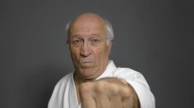 Yaşlı sporcu elleri gri arka planda yumrukları yener.