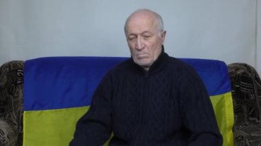Ukrayna bayrağının arka planında yaşlı bir adam Rusya 'nın teröristlerine işaret ediyor.