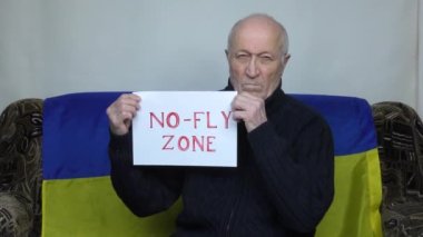 Ukrayna bayrağının arka planında yaşlı bir adam uçuşa yasak bölge ilan ediyor.