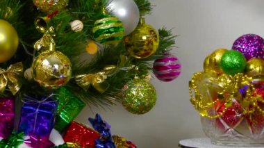 İçinde hediyeler olan bir Noel ağacının yakın plan resmi taşaklı vazoya yaslanmış.