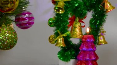 Yanan mumları olan küçük kompozisyon Noel ağacının yanında döner.