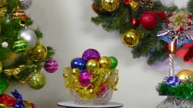Close up of vase with balls between burning candles and christmas tree
