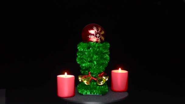 Two Red Burning Candles Red Christmas Ball Rotates Green Stand — Stockvideo