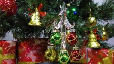 New Year video card a little Christmas tree slowly spins against the background of a green Christmas tree and gifts