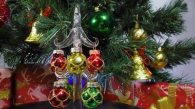 Christmas video card a small decorated Christmas tree is spinning on the background of a large green Christmas tree and gifts