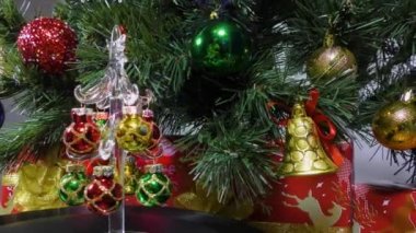 Christmas video card a little Christmas tree is spinning on the background of a green Christmas tree and gifts