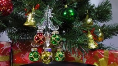 New Year video card a little Christmas tree is spinning on the background of a green Christmas tree and gifts