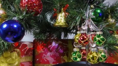 Christmas video card a little Christmas tree slowly spins against the background of a green Christmas tree and gifts