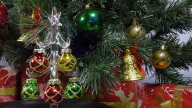 Christmas video card a small decorated Christmas tree slowly spins against the background of a green Christmas tree and gifts