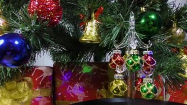 Christmas video card a small decorated Christmas tree is spinning on the background of a green Christmas tree and gifts