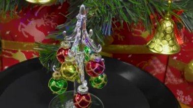 Yeşil bir Noel ağacının arkasındaki video kartı ve hediyeler küçük süslü bir Noel ağacını döndürür.