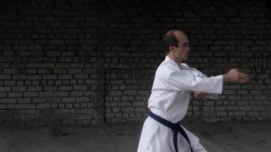 An athlete trains punches and blocks with his hands on a brick wall background