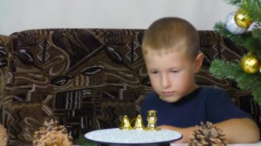 A little boy puts Christmas decorations on a spinning stand