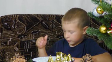 A little boy puts Christmas decorations on a spinning stand