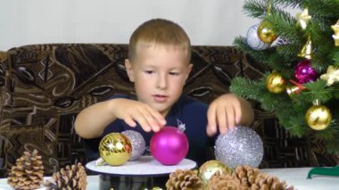 A little boy puts Christmas decorations on a spinning stand