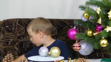 Little boy decorates the Christmas tree with Christmas decorations