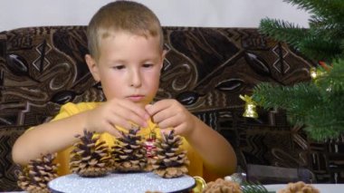 Little boy decorates the Christmas tree with Christmas decorations