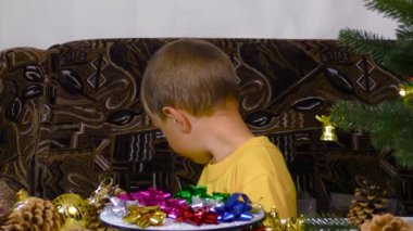 A little boy puts Christmas decorations on a spinning stand