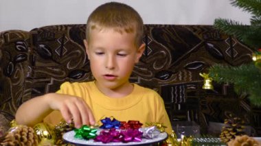 A little boy puts Christmas decorations on a spinning stand