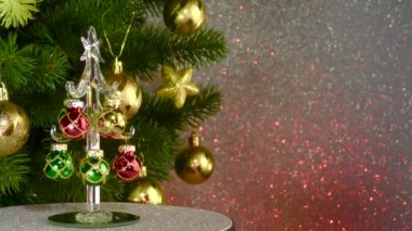 A small Christmas tree rotates near a large decorated Christmas tree