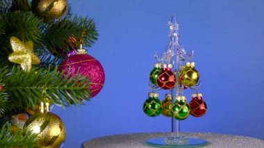 A small Christmas tree rotates near a large decorated Christmas tree