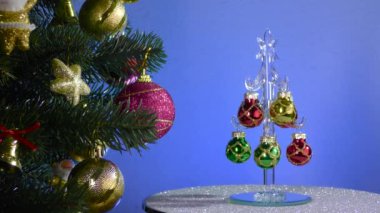 A small Christmas tree rotates near a large decorated Christmas tree
