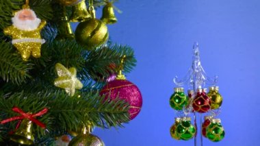 A small Christmas tree rotates near a large decorated Christmas tree
