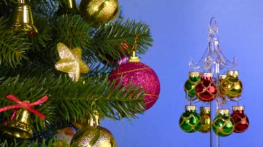 A small Christmas tree rotates near a large decorated Christmas tree
