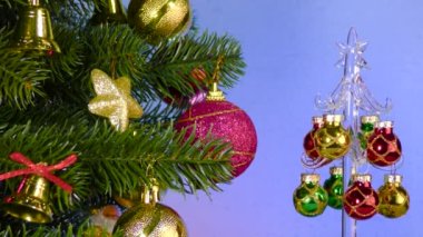 A small Christmas tree rotates near a large decorated Christmas tree