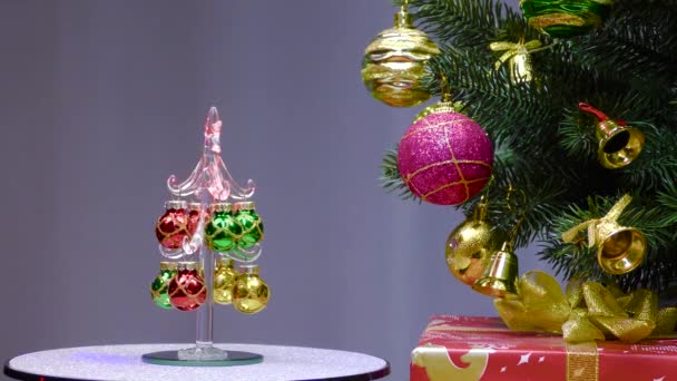 Gray Background Small Christmas Tree Rotates Large Christmas Tree Decorated — Vídeo de stock