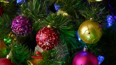 Siyah arka planda, Noel topları olan bir vazo süslü bir Noel ağacının yanında dönüyor.