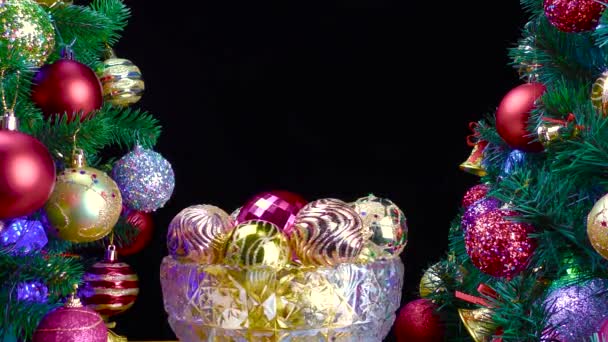 在黑色的背景上 一个装有圣诞球的花瓶在装饰过的圣诞树边旋转着 — 图库视频影像