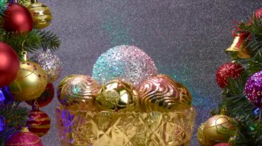 Gümüş arka planda, Noel topları olan bir vazo süslenmiş Noel ağaçlarının yanında dönüyor.