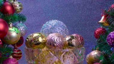Gümüş arka planda, Noel topları olan bir vazo süslenmiş Noel ağaçlarının yanında dönüyor.