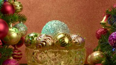 Kırmızı arka planda, Noel topları olan bir vazo süslü Noel ağaçlarının yanında dönüyor.