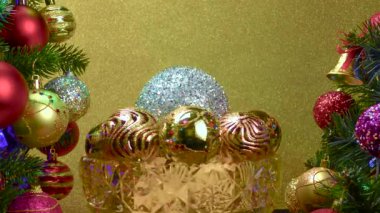 Sarı arka planda, Noel topları olan bir vazo süslü Noel ağaçlarının yanında dönüyor.