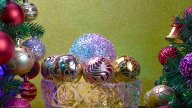 Sarı arka planda, Noel topları olan bir vazo süslü Noel ağaçlarının yanında dönüyor.