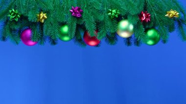 Mavi arka planda, Noel ağacı dalları Noel süslemeleri ile süslenmiş.