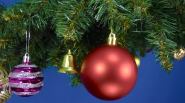 Noel süslemeleri ile süslenmiş Noel ağacı dalları mavi arka planda dönüyor