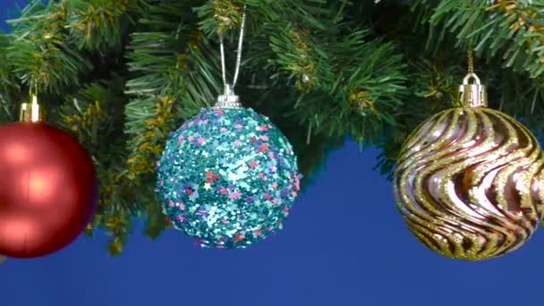 用圣诞装饰品装饰的圣诞树树枝在蓝色的背景上旋转 — 图库视频影像