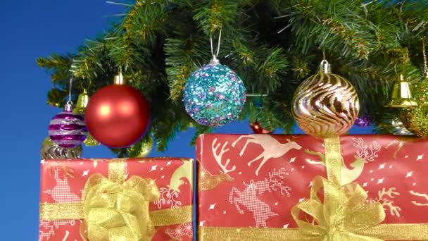 Auf Blauem Hintergrund Mit Weihnachtsschmuck Und Großen Geschenkschachteln Verzierte Christbaumzweige — Stockvideo