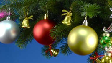 Mavi arka planda, Noel ağacı dallarının yanında, küçük bir Noel ağacı gri bir stantta dönüyor.