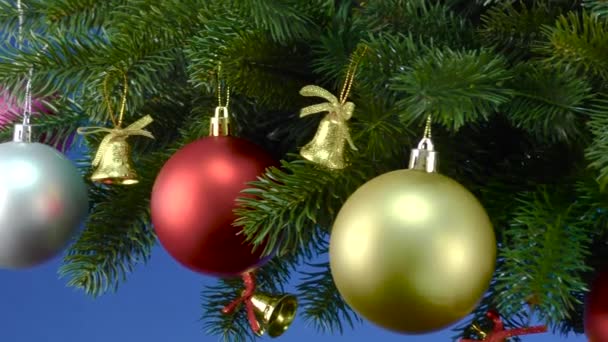 Auf Blauem Grund Der Nähe Der Weihnachtsbaumzweige Mit Weihnachtsschmuck Dreht — Stockvideo