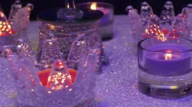 Küçük bir Noel ağacının etrafındaki gri bir yüzeyde, standlarda yanan mumlar.