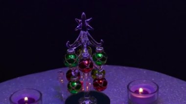 Küçük bir Noel ağacının etrafındaki gri bir yüzeyde, standlarda yanan mumlar.