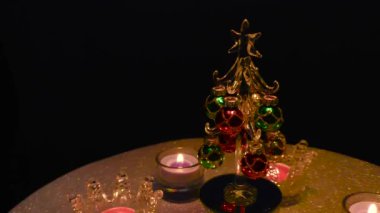 Küçük bir Noel ağacının etrafındaki gri bir yüzeyde, standlarda yanan mumlar.