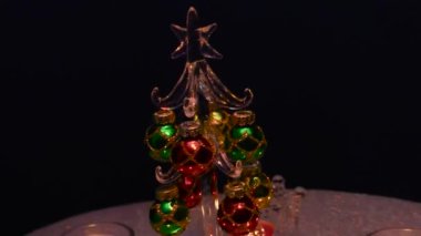 Küçük bir Noel ağacının etrafındaki gri bir yüzeyde, standlarda yanan mumlar.