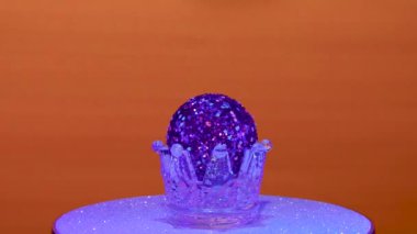 Kırmızı arka planda, Noel topu gümüş bir stantta döner.