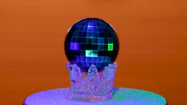 Kırmızı arka planda, Noel topu gümüş bir stantta döner.