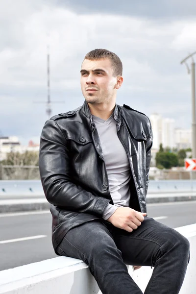 Young man sitting alongside a road — Stock Photo, Image